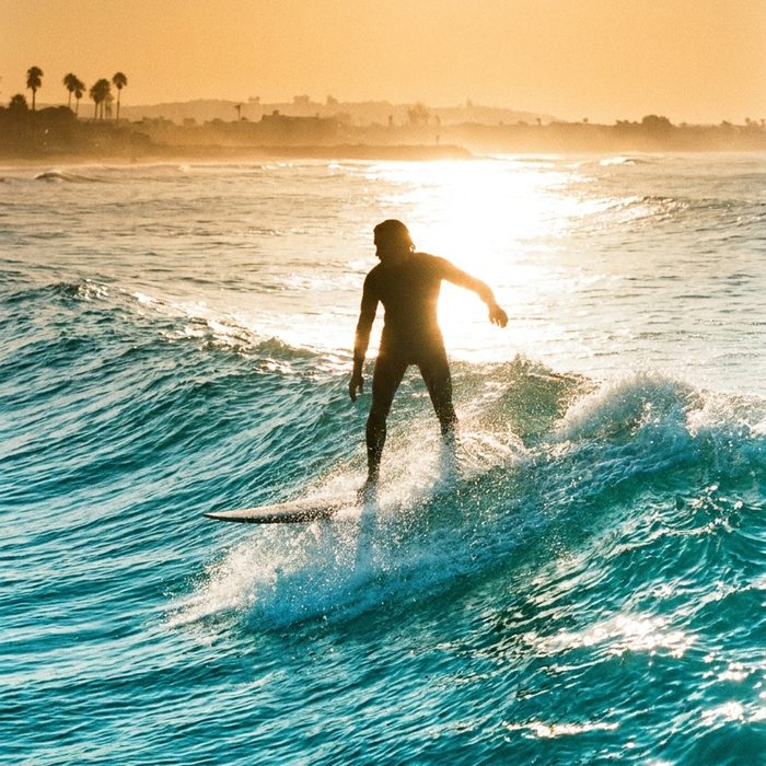 Business Motivation: Surfer im Gegenlicht auf einer langen Welle